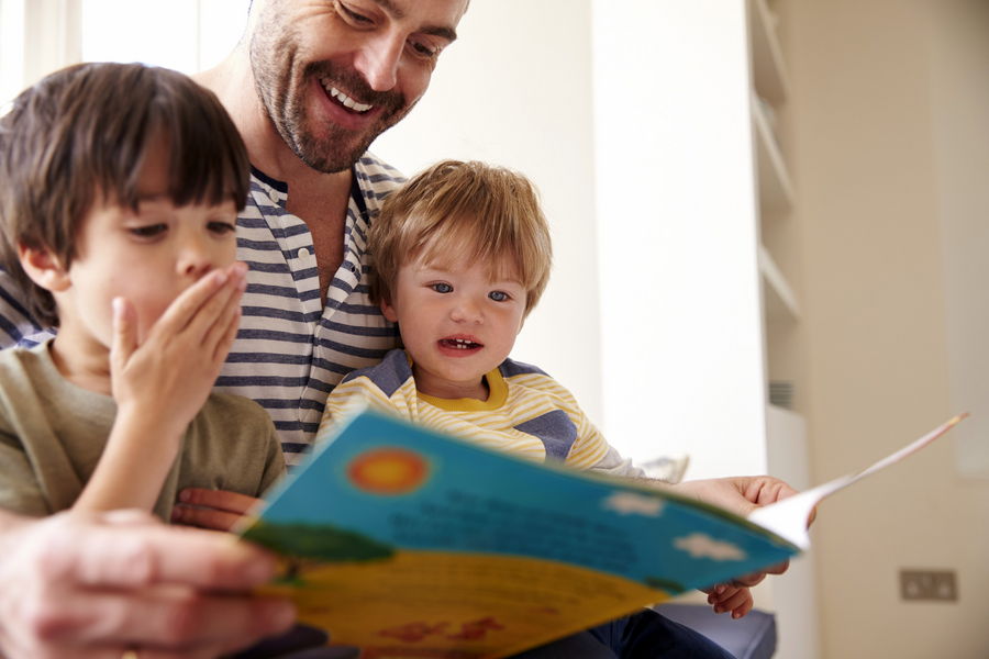 Kinder lesen mit dem Vater ein englisches Kinderbuch (Foto: Monkey Business Images/Shutterstock.com)